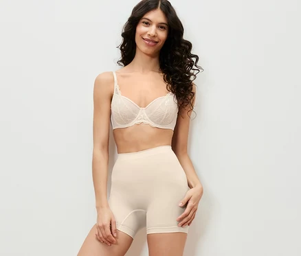 Kobieta pozuje w bieliźnie i spodenkach modelujących figurę.