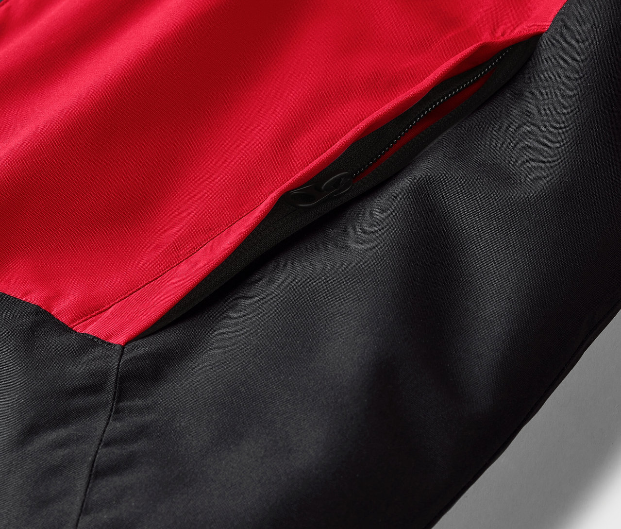 Zbliżenie czerwono-czarnej kurtki z kieszenią na zamek.