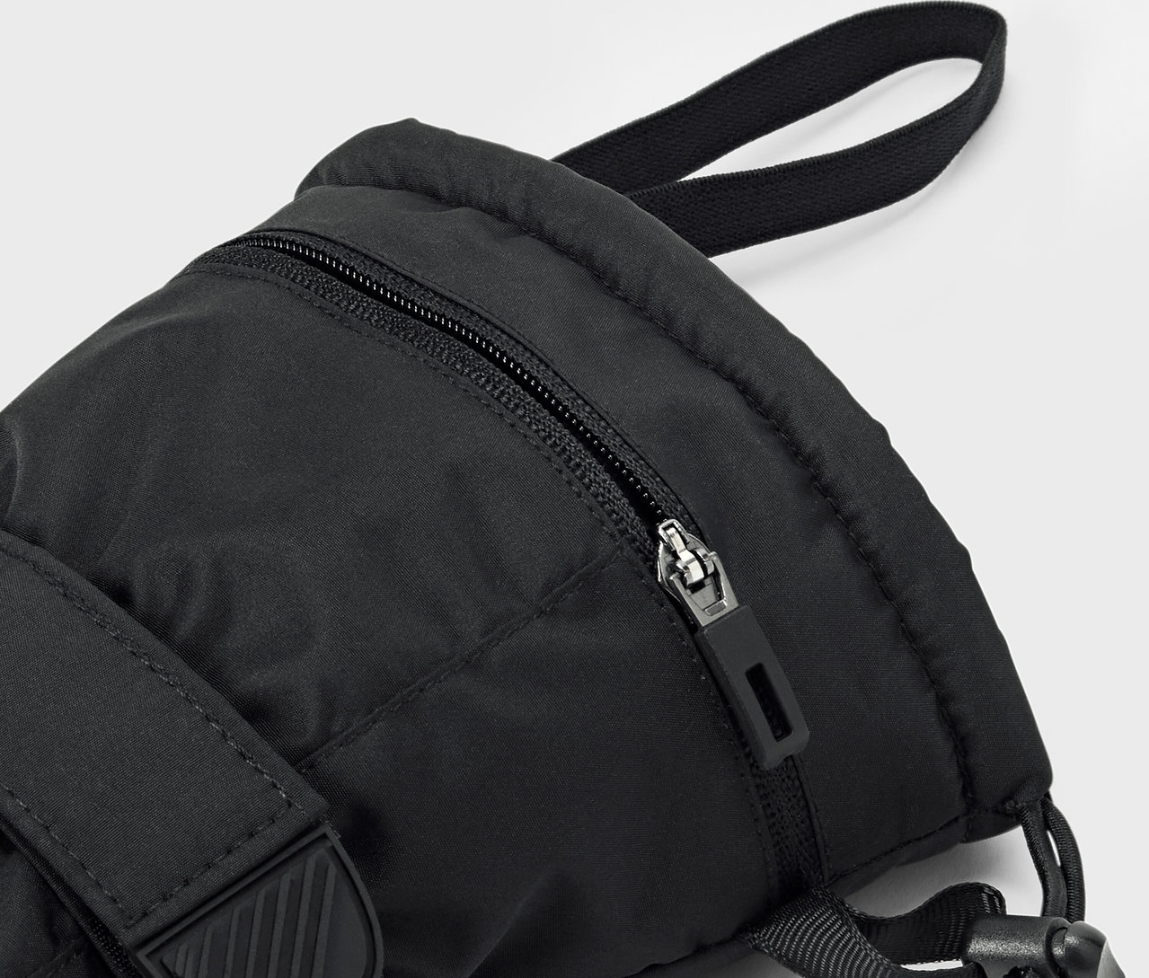 Zbliżenie na czarny plecak z widocznym zamkiem błyskawicznym i paskiem.