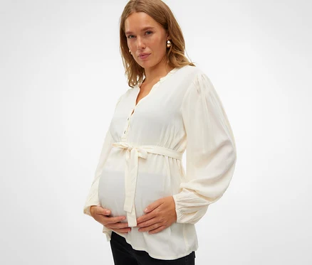 Kobieta w ciąży trzyma się za brzuch, ma na sobie bluzkę MAMALICIOUS MLMERCY LIA L/S WO TOP 2F NOOS.