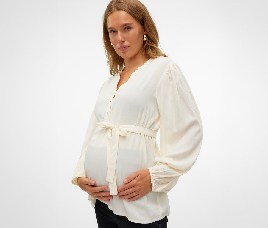 Kobieta w ciąży trzyma się za brzuch, ma na sobie bluzkę MAMALICIOUS MLMERCY LIA L/S WO TOP 2F NOOS.