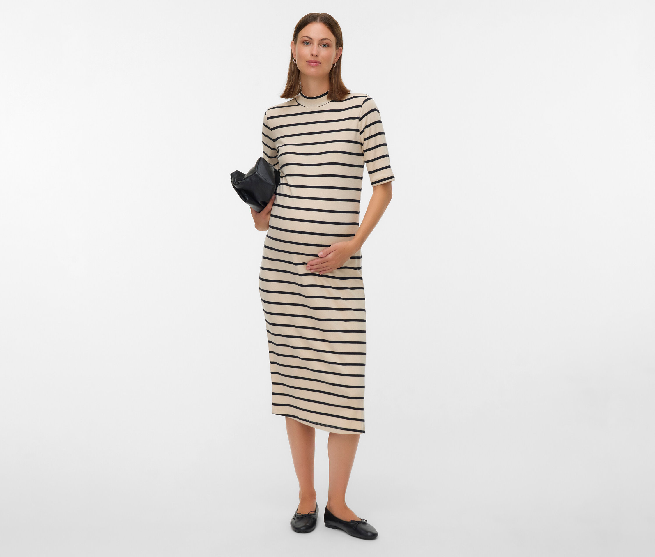 Kobieta w ciąży w sukience w paski trzyma czarną torebkę.