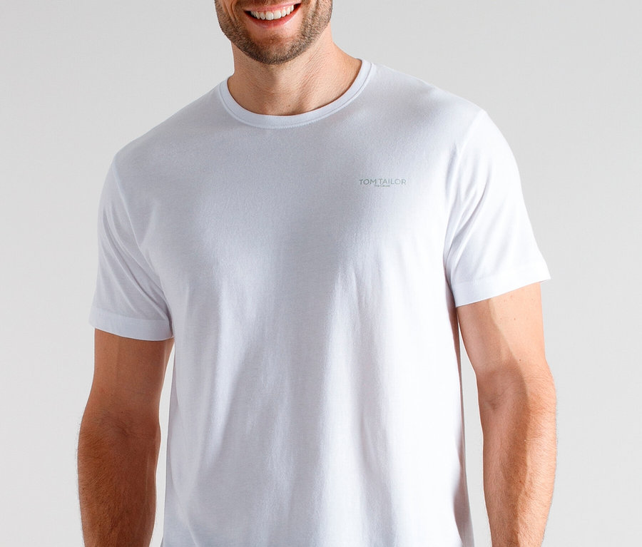 Uśmiechnięty mężczyzna ma na sobie biały T-shirt i spodnie od piżamy w kratę.