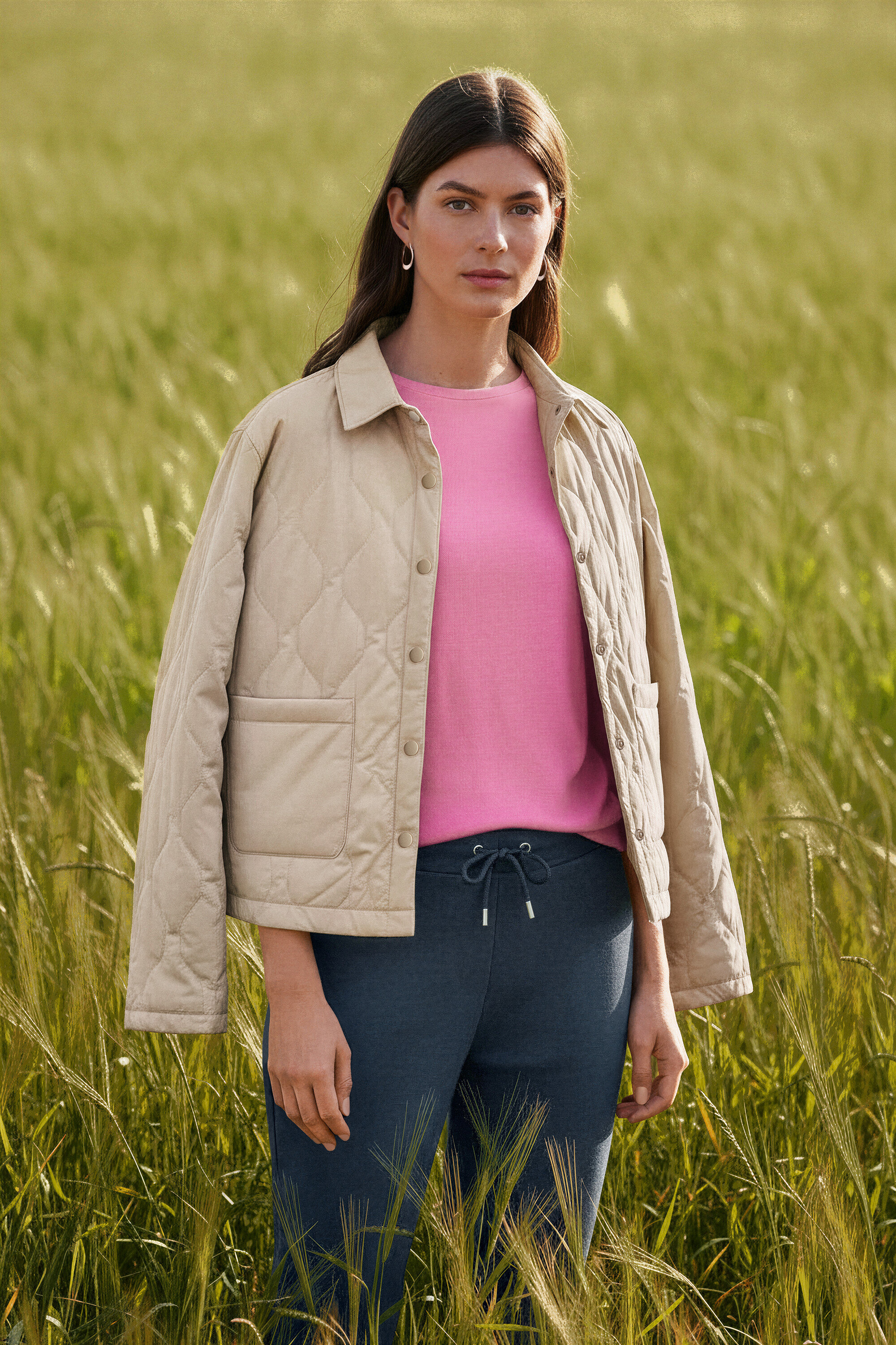 Kobieta stoi na polu i nosi kolczyki kreole Wave.