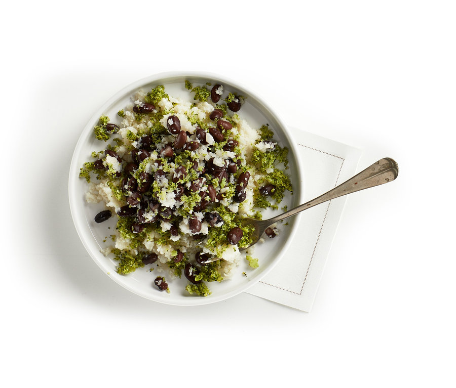 Talerz z ryżem, warzywami i fasolą. Na talerzu leży łyżka. Rozdrabniacz do warzyw.