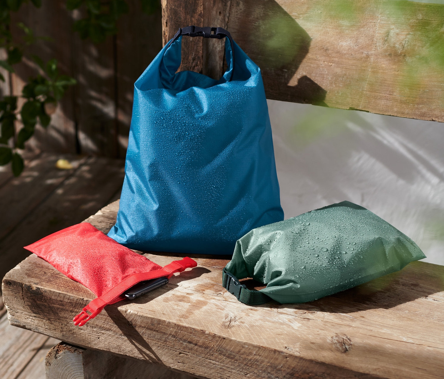 Na drewnianej ławce leżą 3 wodoodporne worki.