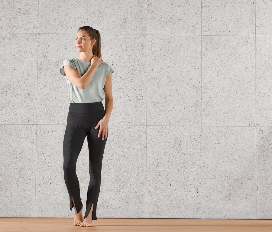 Kobieta pozuje w czarnych spodniach sportowych z rozszerzanymi nogawkami z rozcięciem.