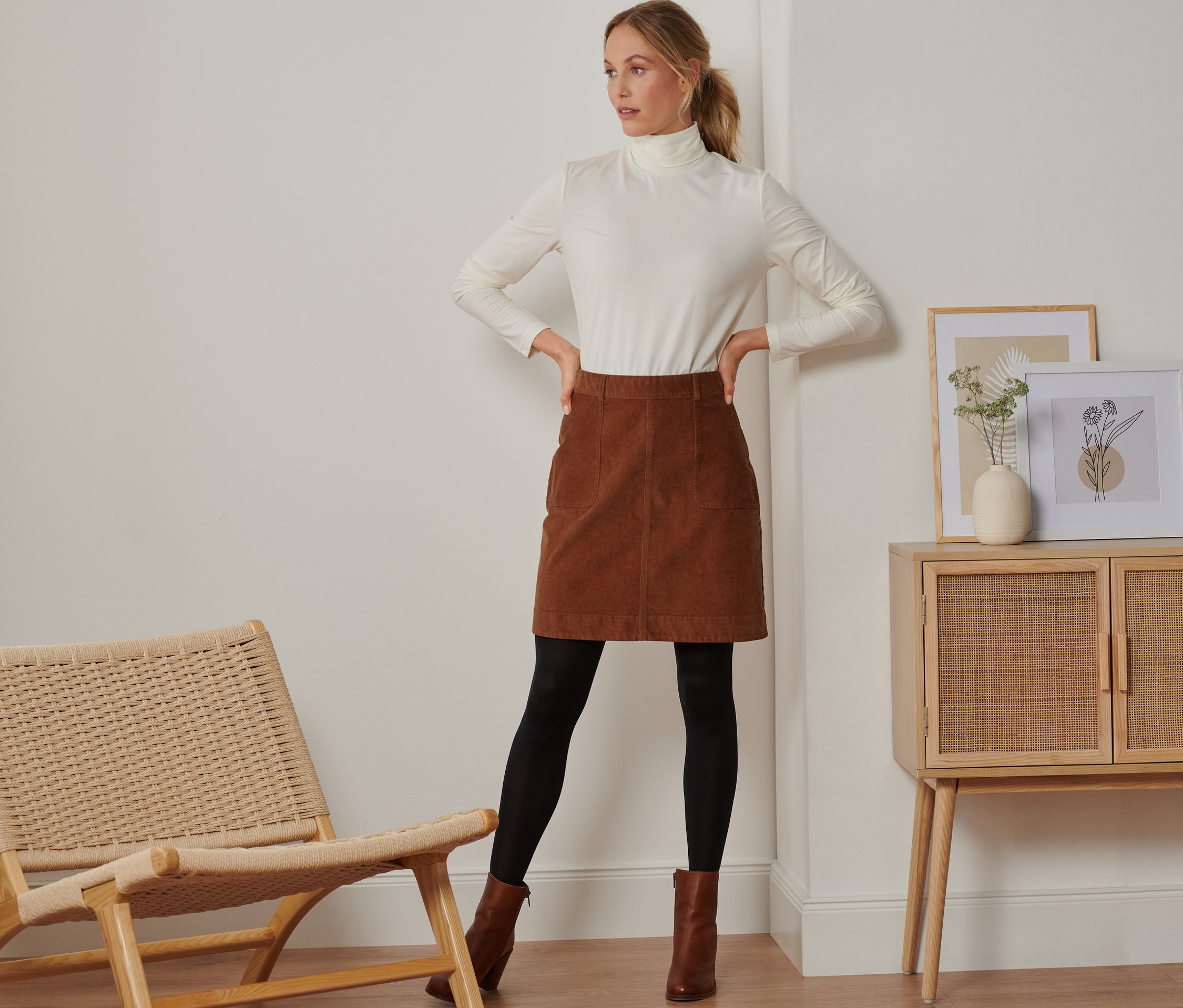 Kobieta pozuje w brązowej spódnicy ze sztruksu.