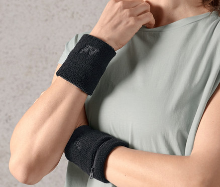 Kobieta ma na obu nadgarstkach czarne frotki, 2 sztuki.