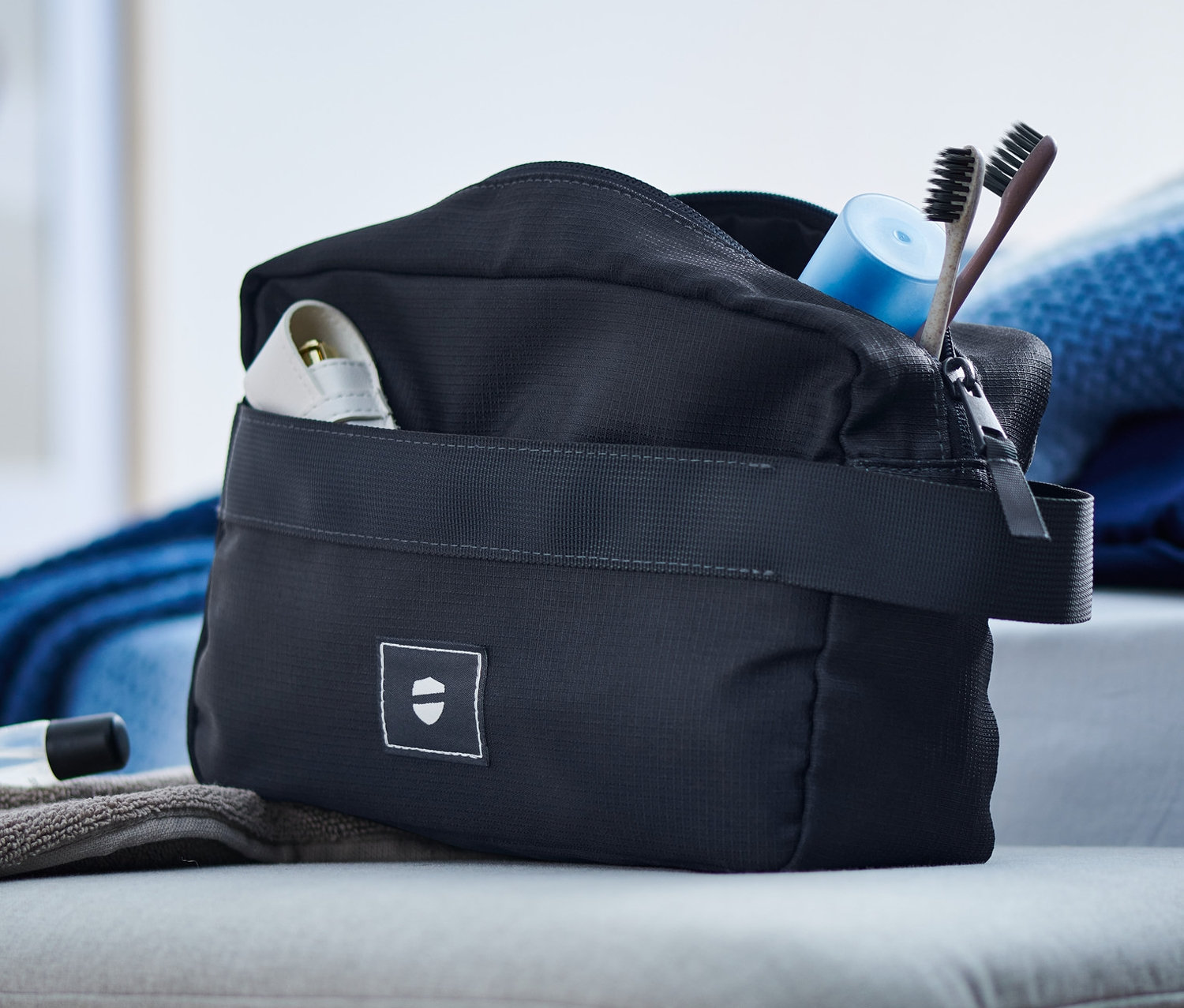 Na taborecie leżą kosmetyczka, ręcznik i kosmetyki.