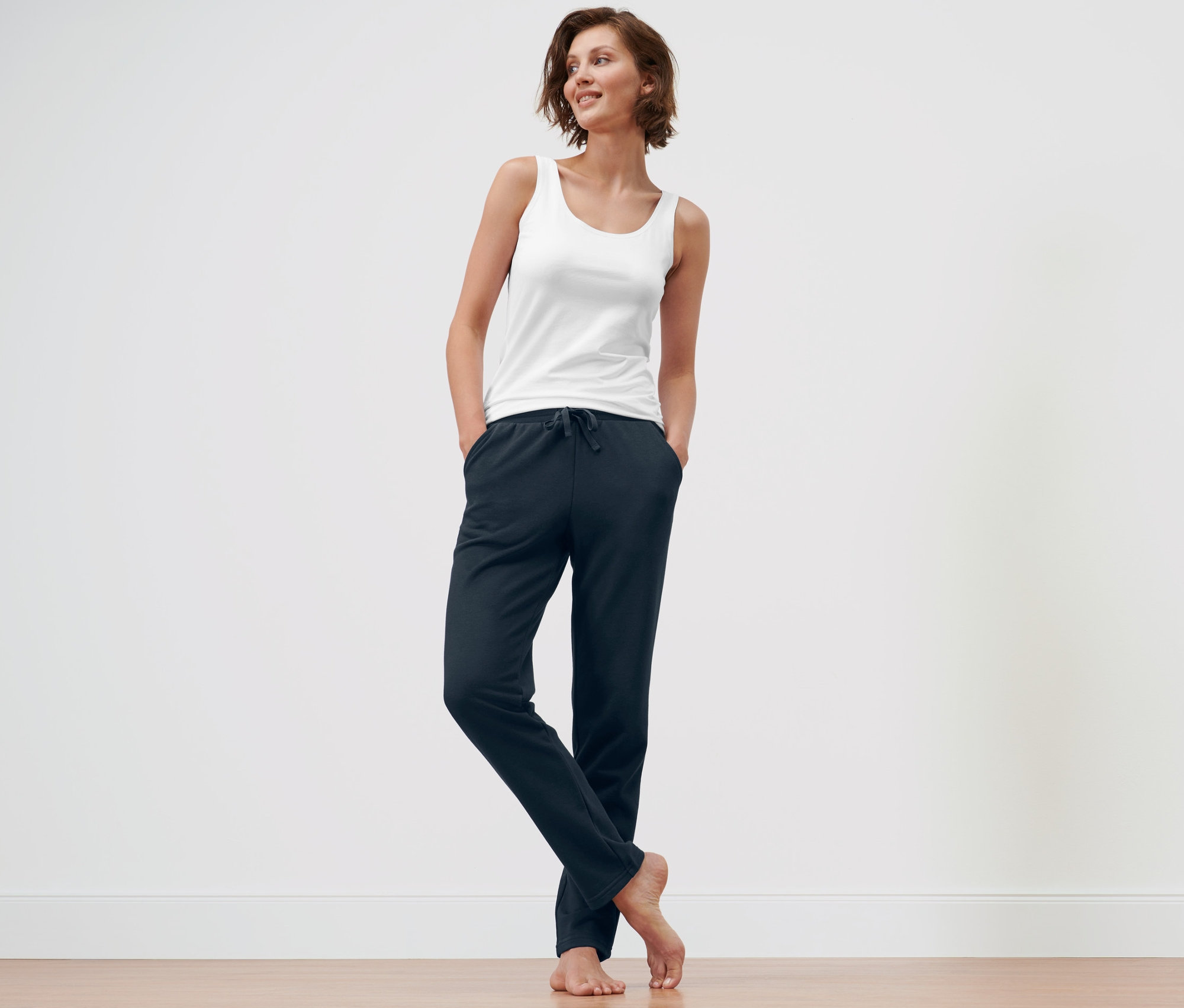 Kobieta stoi z rękami w kieszeniach granatowych spodni rekreacyjnych i niebieskich spodni rekreacyjnych.