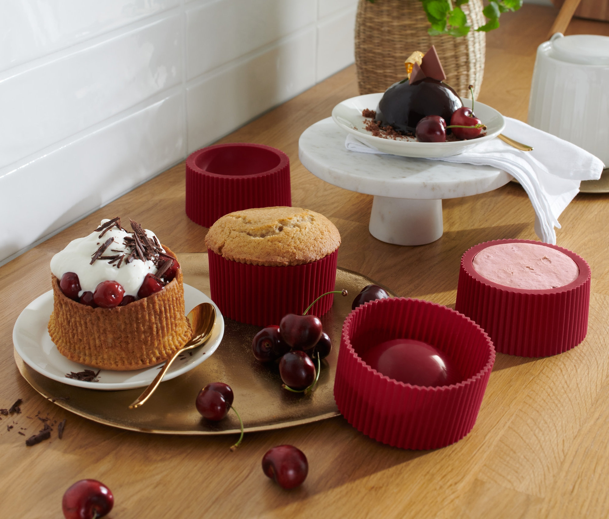 Na drewnianym stole znajdują się 4 foremki do deserów i talerze z gotowymi deserami.