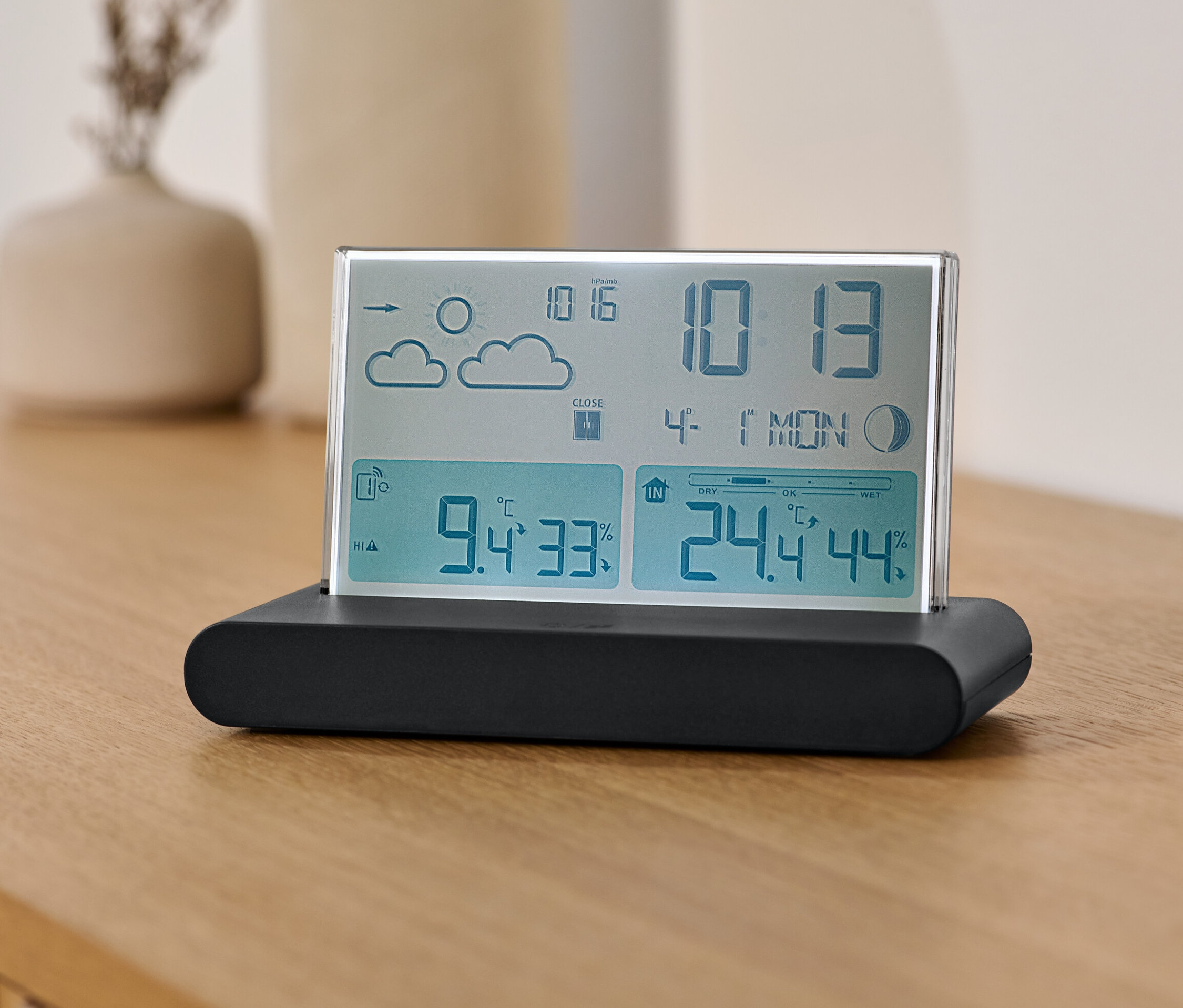 Radiowa stacja pogodowa z czujnikiem zewnętrznym stoi na drewnianym stole.
