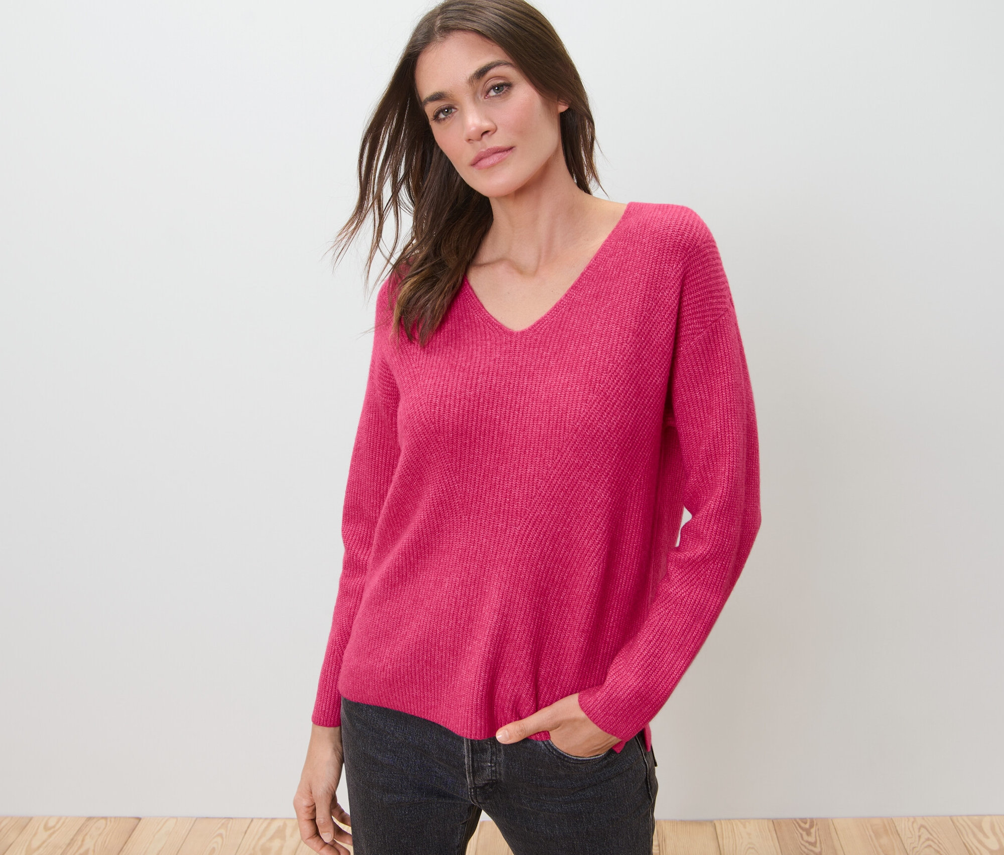 Kobieta pozuje w malinowym swetrze o grubym splocie.