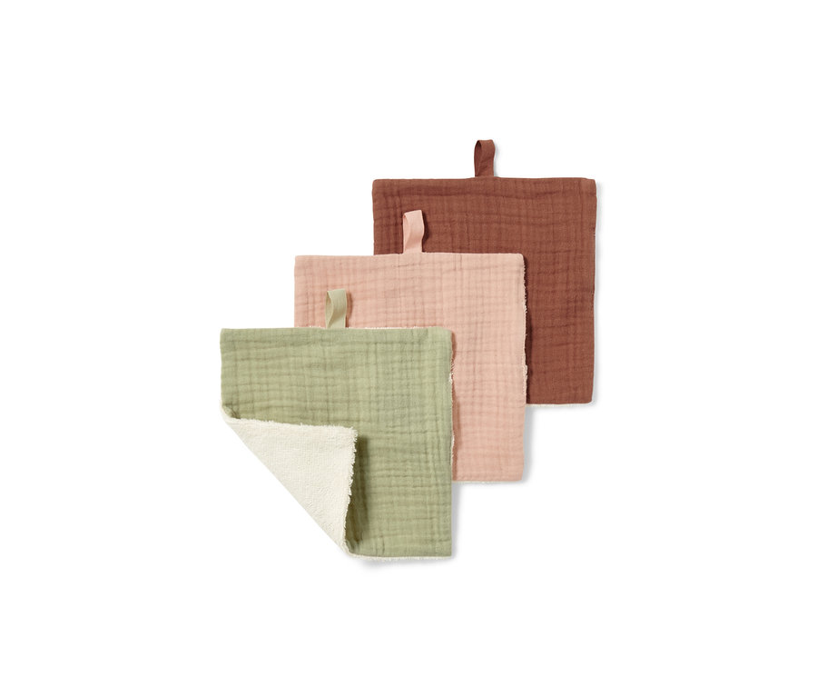 Widoczne są trzy ściereczki kosmetyczne w kolorach: zielonym, różowym i rdzawym. Zielona ściereczka jest częściowo złożona, dzięki czemu widoczna jest biała strona.