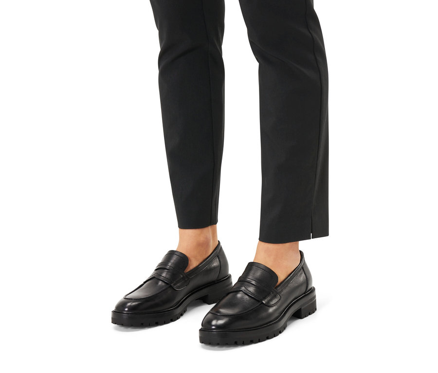 Stopy w czarnych spodniach i skórzanych loafersach.