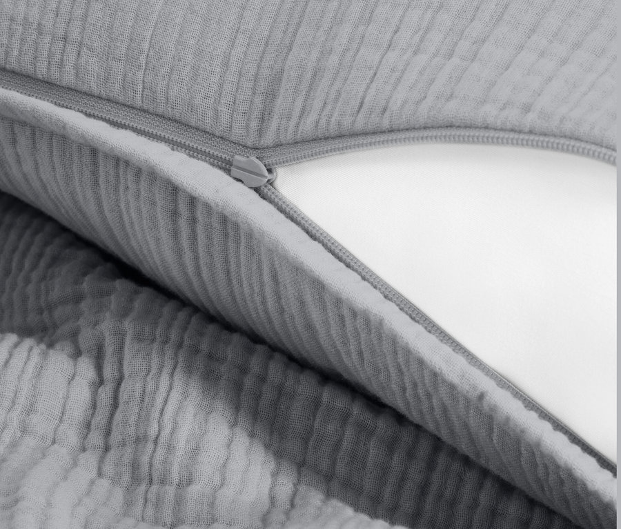 Zbliżenie szarej pościeli muślinowej z zamkiem błyskawicznym.