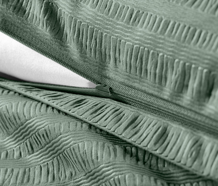Zbliżenie na zieloną pościel z kory o standardowym rozmiarze z zamkiem błyskawicznym i białym wypełnieniem.