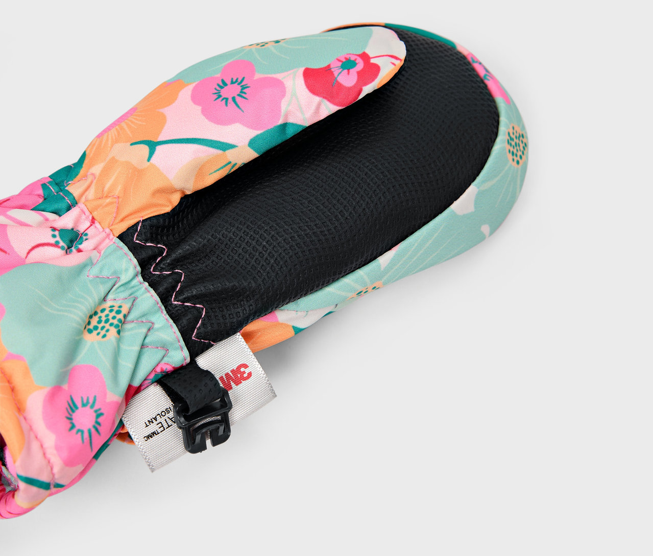 Szczegół kolorowej, kwiatowej rękawicy z czarną podszewką i regulowanym paskiem.