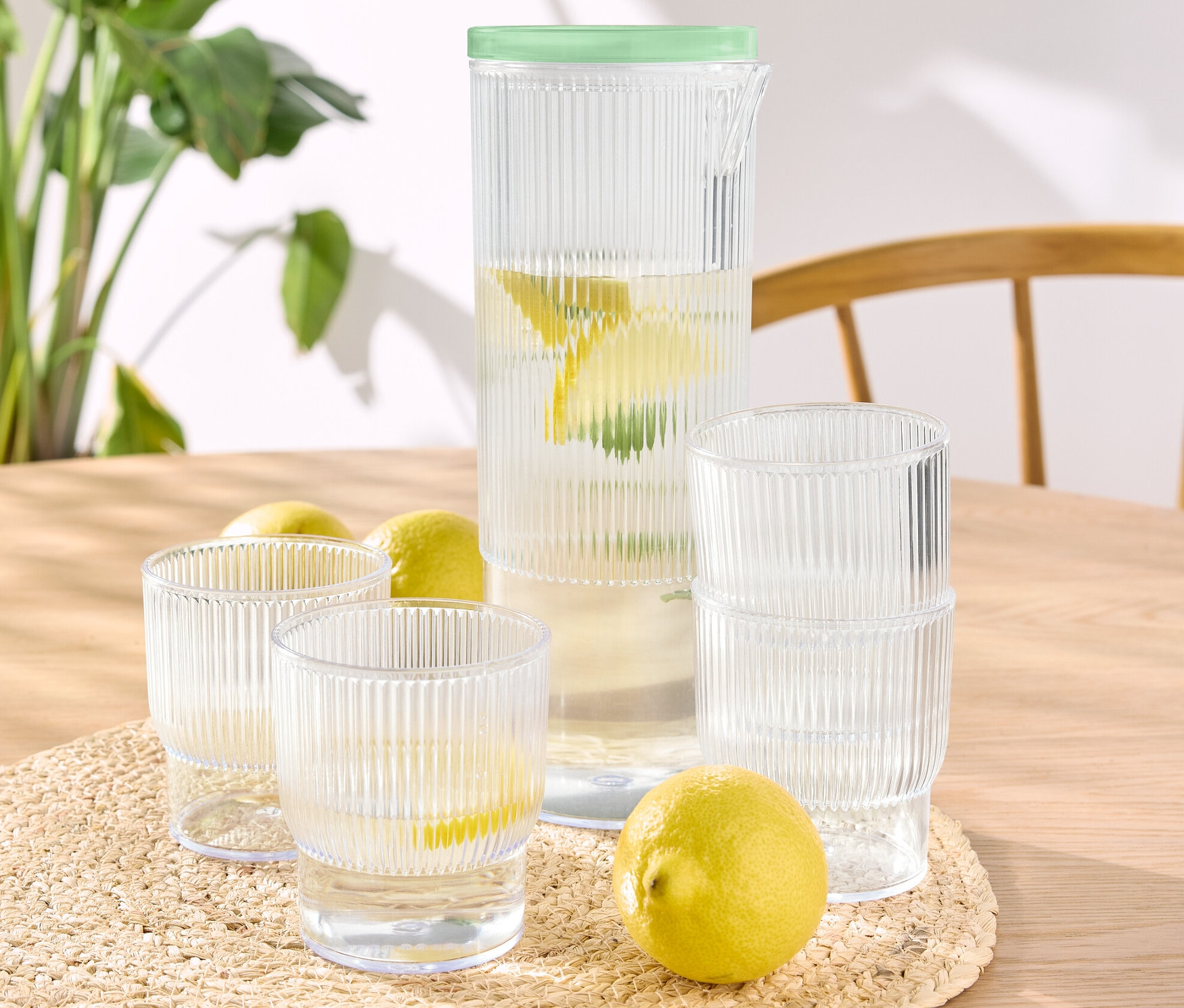 Na stole stoją szklanki z tworzywa sztucznego z dzbankiem (4 sztuki), niektóre wypełnione wodą z cytryną.