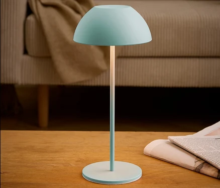 Turkusowa lampa stoi na stole obok gazety.