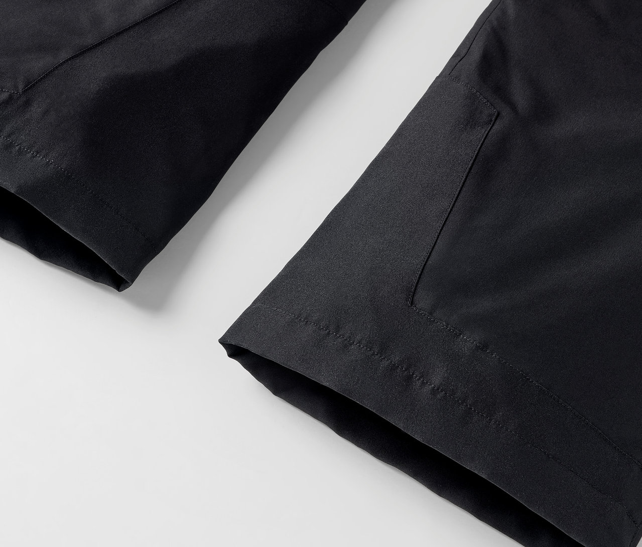 Szczegół czarnych spodni z kieszenią na białym tle.