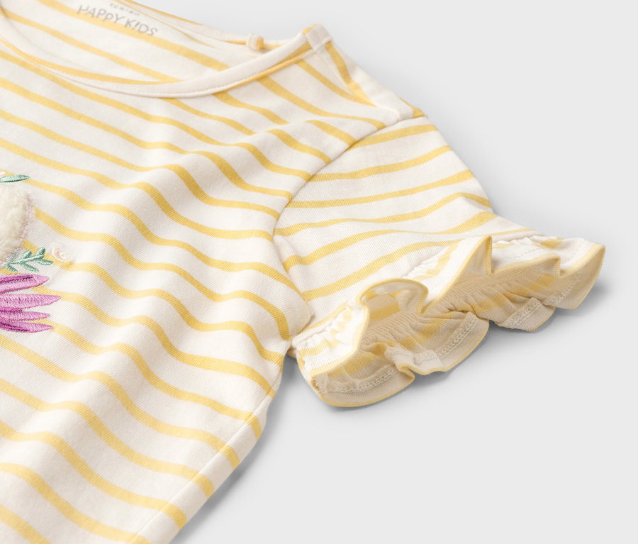 Zdjęcie detalu żółto-białej koszulki w paski z krótkim rękawem i fioletowym wzorem kwiatowym.