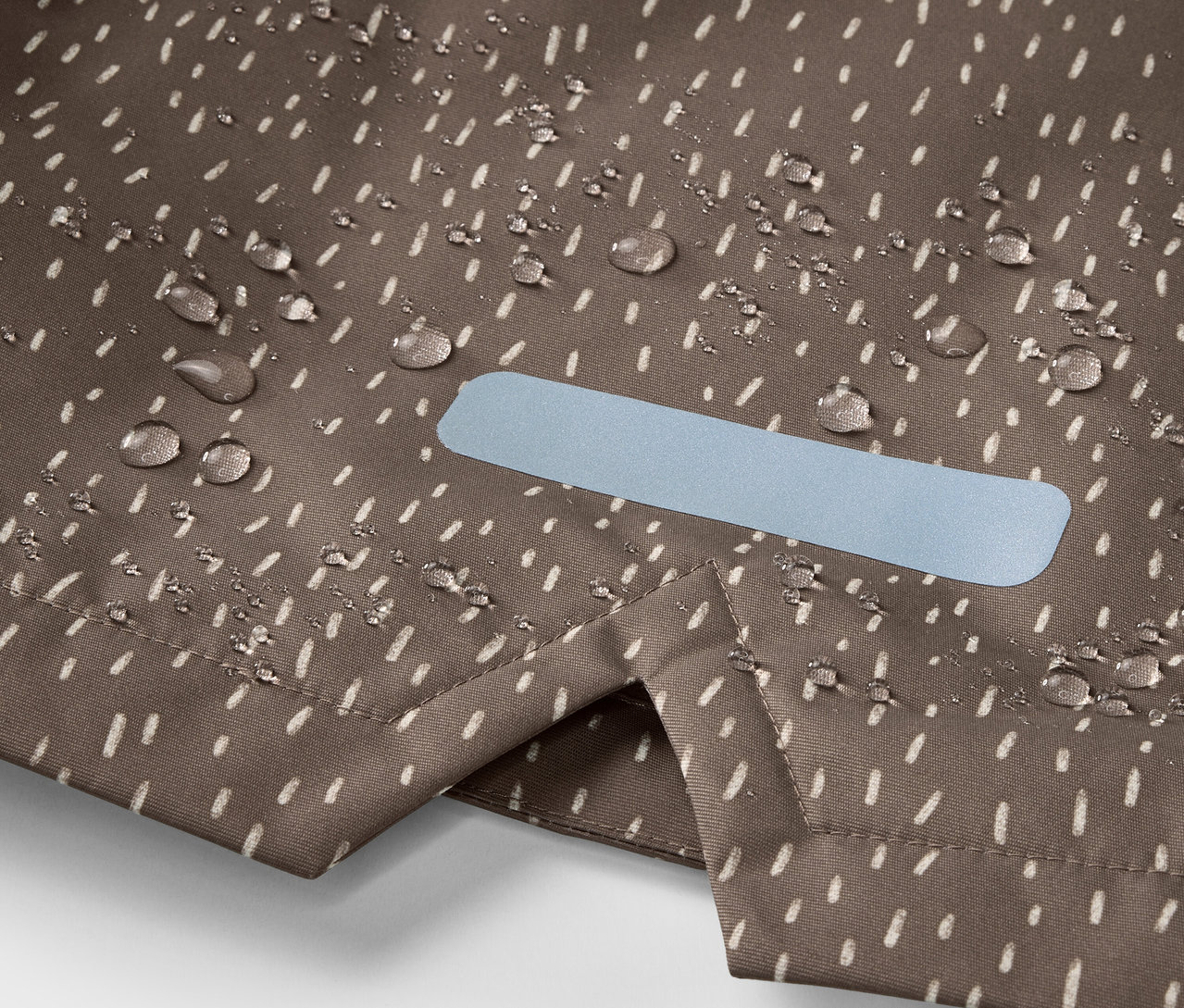 Zbliżenie na przeciwdeszczową termoaktywną kurtkę z kroplami wody i elementem odblaskowym.