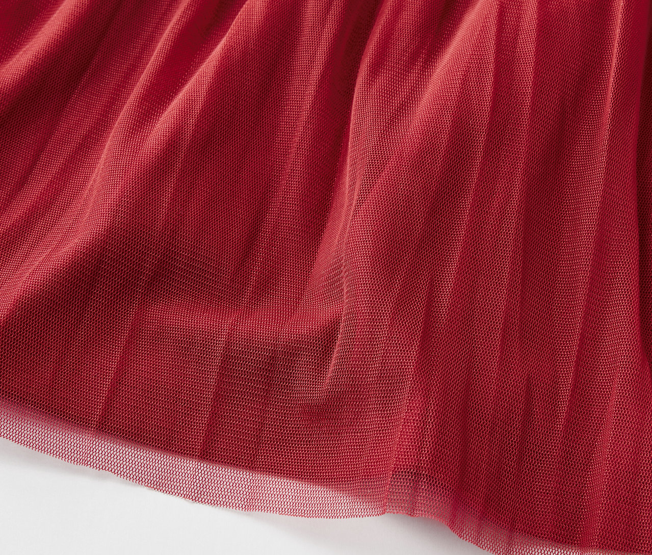 Zbliżenie na bordową tkaninę tiulową o warstwowej fakturze.