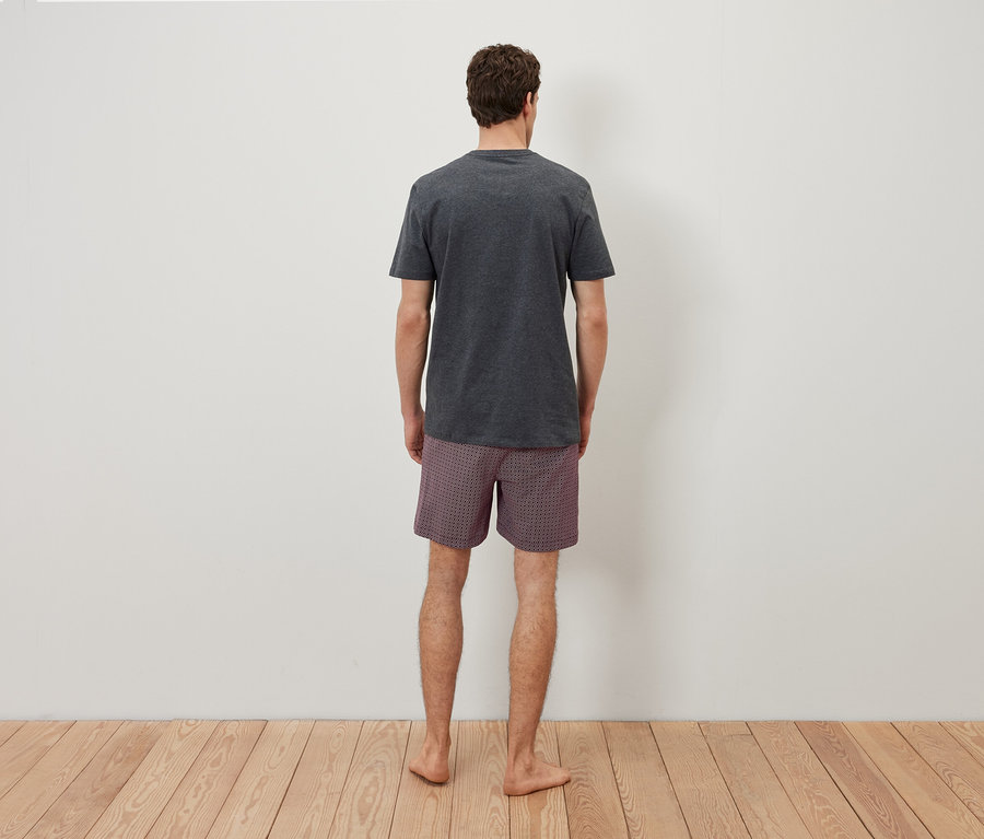 Mężczyzna tyłem do kamery ma na sobie szarą koszulkę i szarą koszulkę w kratę.