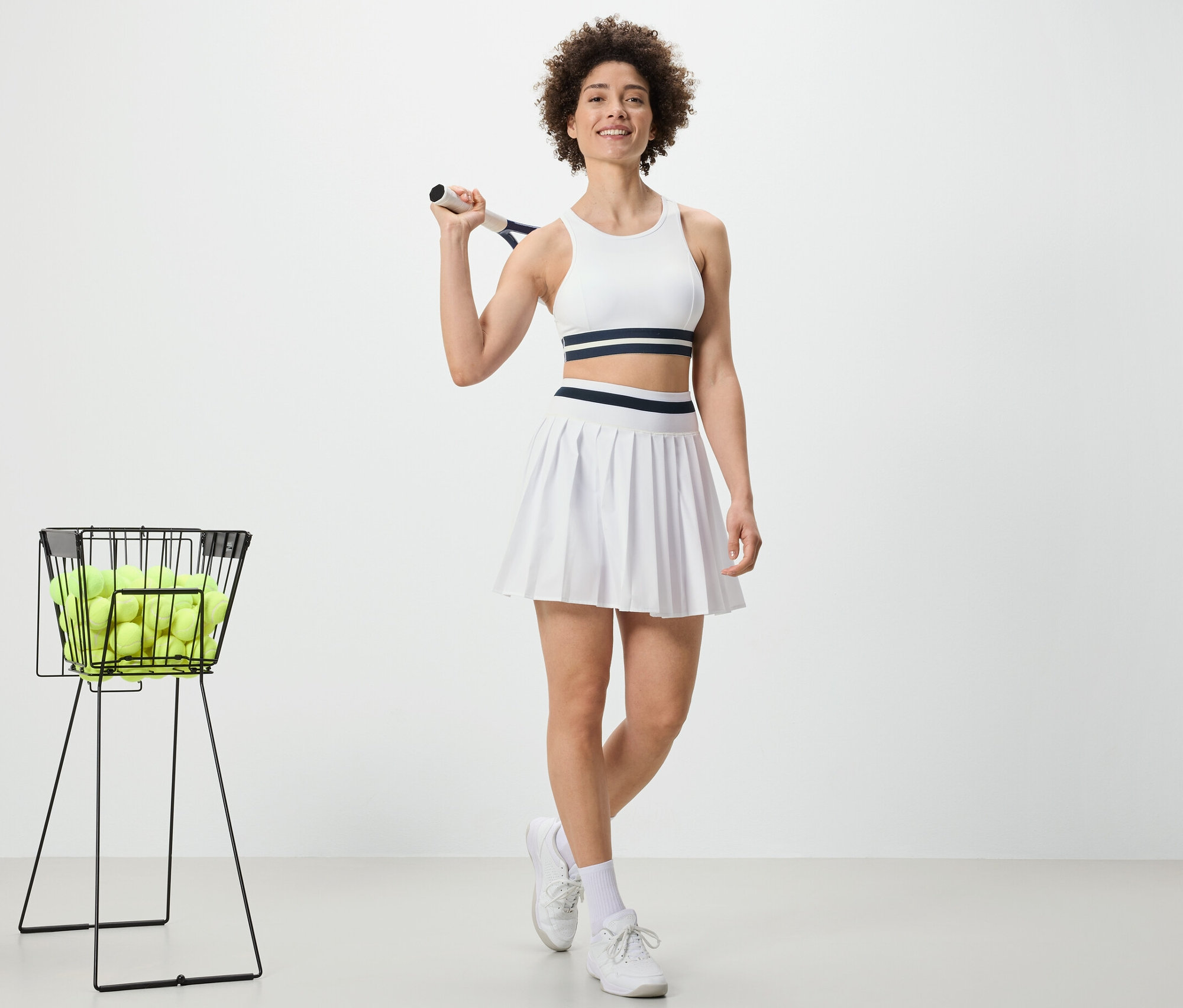 Kobieta trzyma rakietę tenisową i ma na sobie spódnicę sportową.