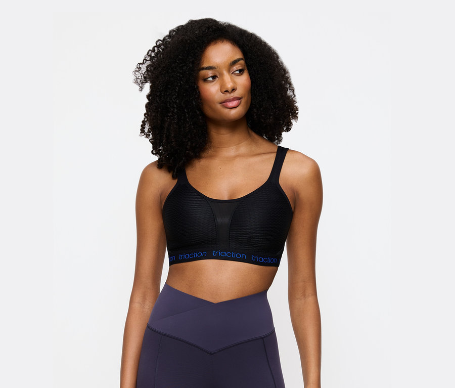 Kobieta ma na sobie czarny biustonosz sportowy Triaction i fioletowe legginsy.