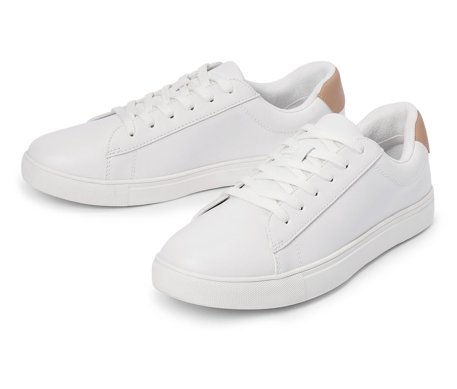 Dwa białe tenisówki ze sznurówkami i jasnobrązowym detalem na pięcie leżą obok siebie.