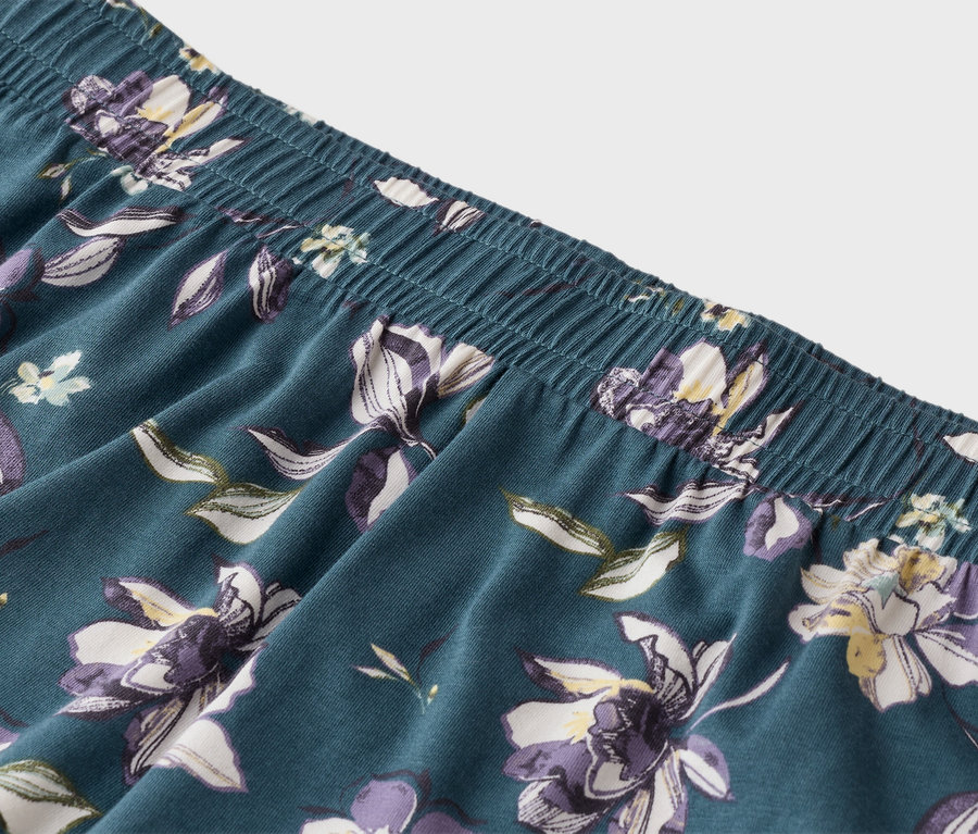 Bliskie ujęcie niebieskich spodni od piżamy z elastycznym pasem i kwiatowym wzorem.