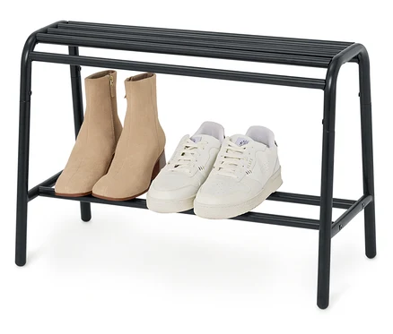Na czarnym regale na buty stoi para beżowych botków i para białych tenisówek.