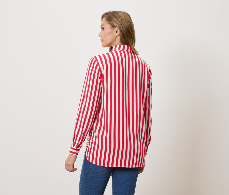 Kobieta od tyłu w bluzce w czerwono-białe paski i dżinsach.