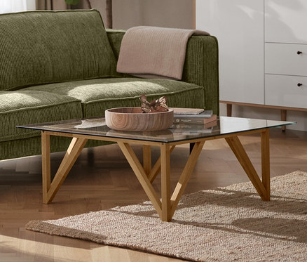 Zielona 3-osobowa sofa sztruksowa w salonie, obok czarna lampa sufitowa z metalu i biała szafka typu highboard »Bekeson«.