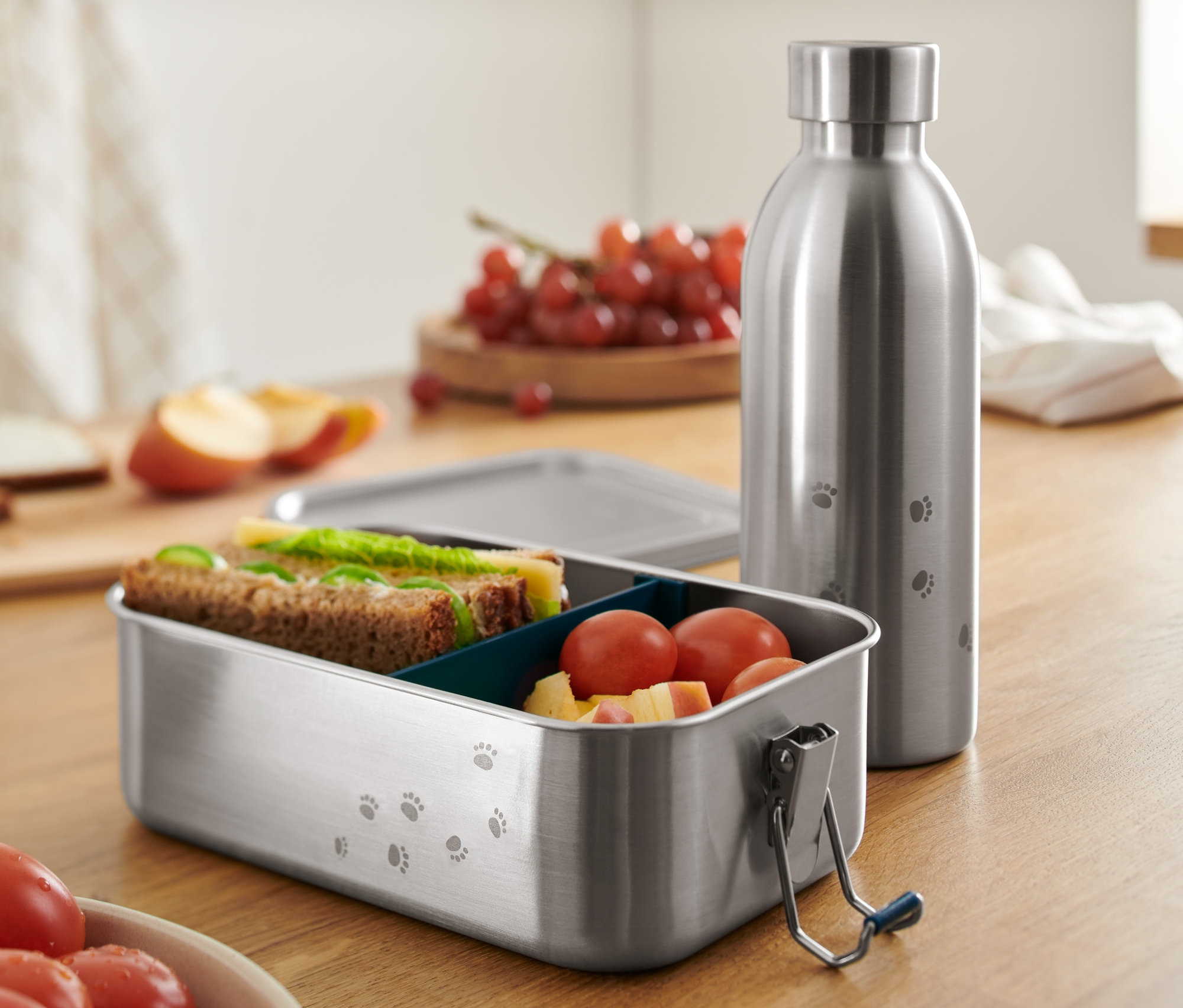 Pojemnik na kanapki i bidon ze stali nierdzewnej na drewnianym stole.