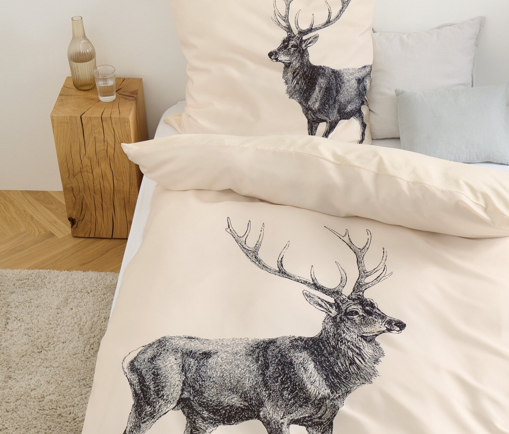 Beżowa pościel we wzór jelenia leży na łóżku.