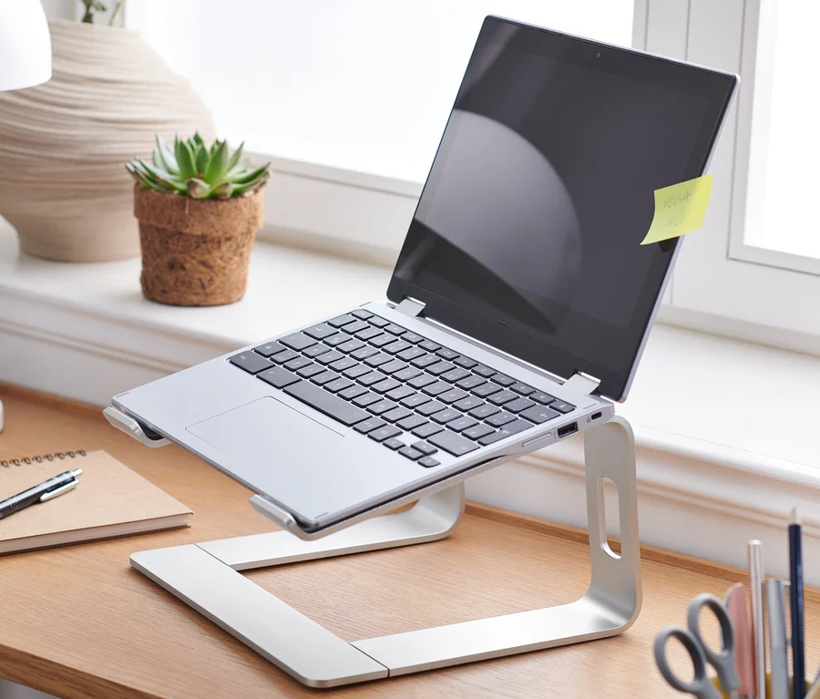 Laptop na stojaku na laptopa na drewnianym stole.