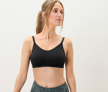 Kobieta w pozycji drzewa ma na sobie bezszwowy biustonosz sportowy.