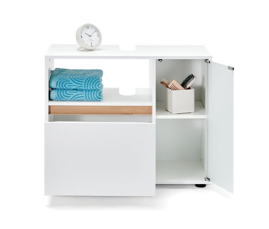 Biała szafka pod umywalkę z ręcznikami i kosmetykami.