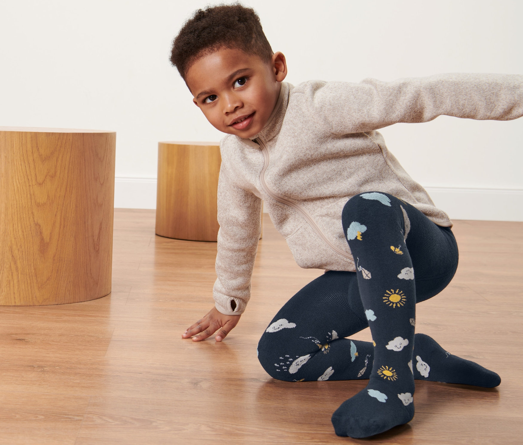 Chłopiec w termoaktywnych rajstopach w chmurki klęczy na podłodze.