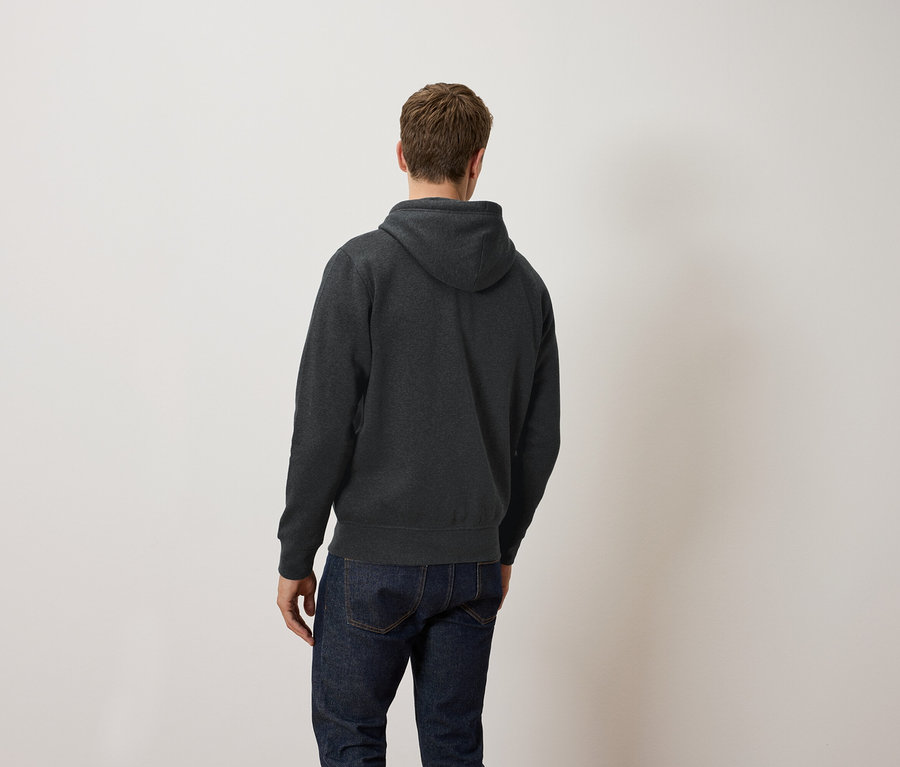Mężczyzna tyłem do kamery ma na sobie ciemnoszarą bluzę z kapturem i dżinsy.