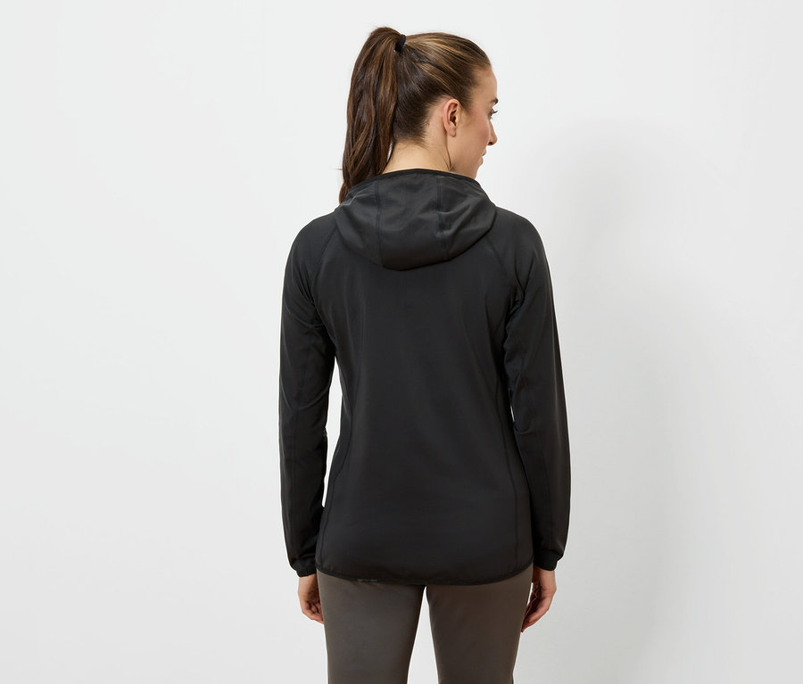 Kobieta tyłem do kamery ma na sobie czarną kurtkę z kapturem i ciemne spodnie.