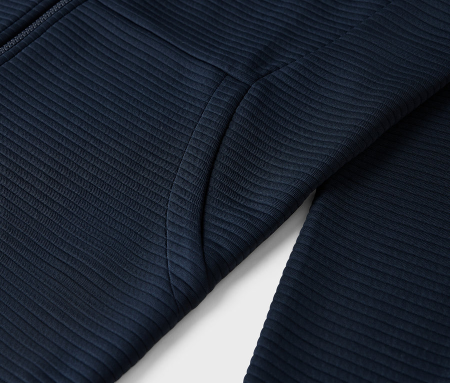 Zbliżenie na granatową, prążkowaną kurtkę z zamkiem błyskawicznym i kieszenią.