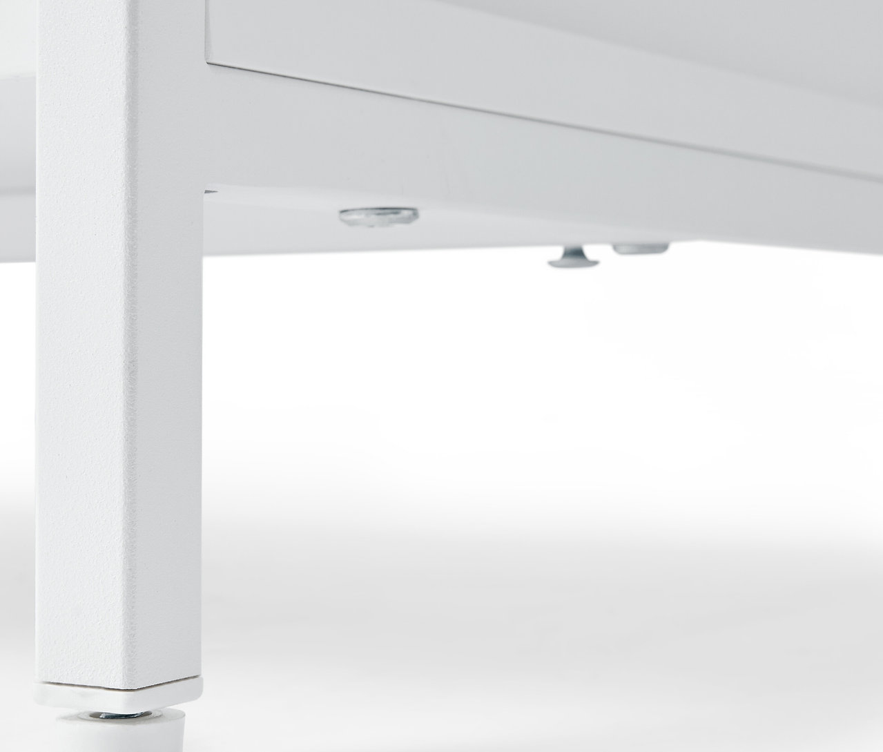 Szczegół białej komody »KLAAR« z 4 szufladami, widok od dołu na nóżki.