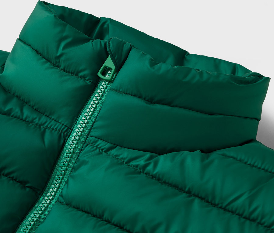 Zbliżenie na zieloną kurtkę puchową z kołnierzem i zamkiem błyskawicznym.