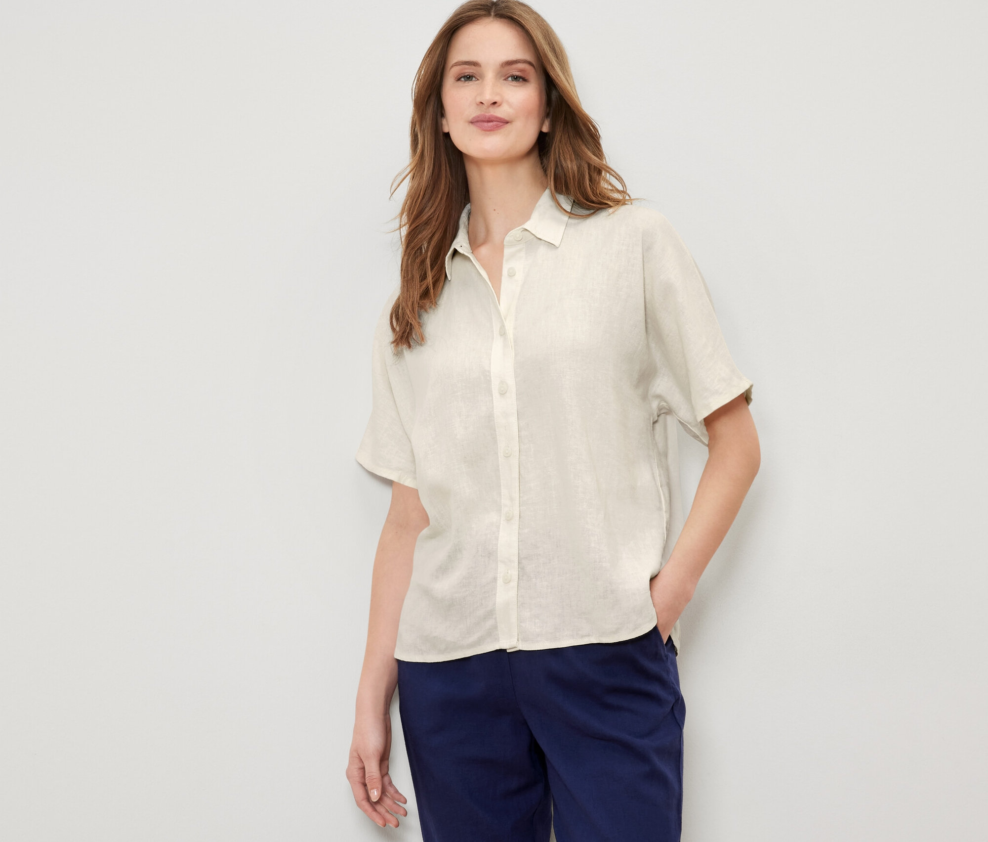 Kobieta pozuje w kremowej lnianej bluzce.