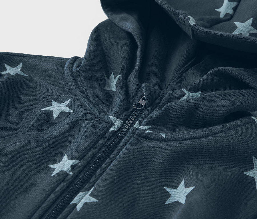 Zbliżenie granatowej bluzy z kapturem zapinanej na zamek, w gwiazdki.